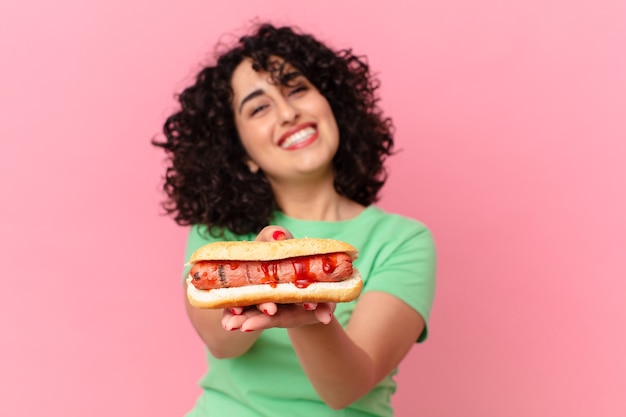 Ładna arabska kobieta trzyma hot doga. koncepcja fast food