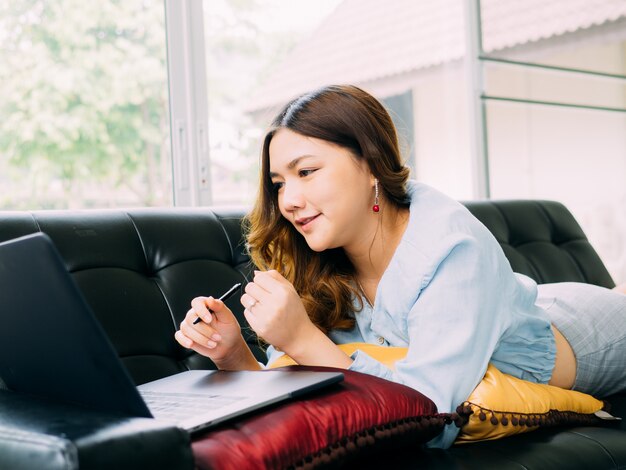 Ładna azjatykcia kobieta interneta online praca w domu i relaksuje styl życia z jej labtop