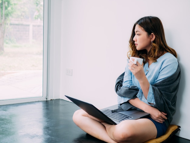 Ładna azjatykcia kobieta interneta online praca w domu i relaksuje styl życia z jej labtop