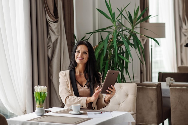 Ładna biznesowa kobieta za pomocą tabletu do pracy podczas przerwy na kawę w kawiarni
