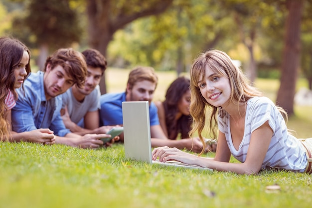 Ładna blondynka używa laptop w parku