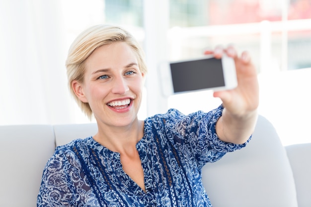 Ładna blondynki kobieta bierze selfie w żywym pokoju