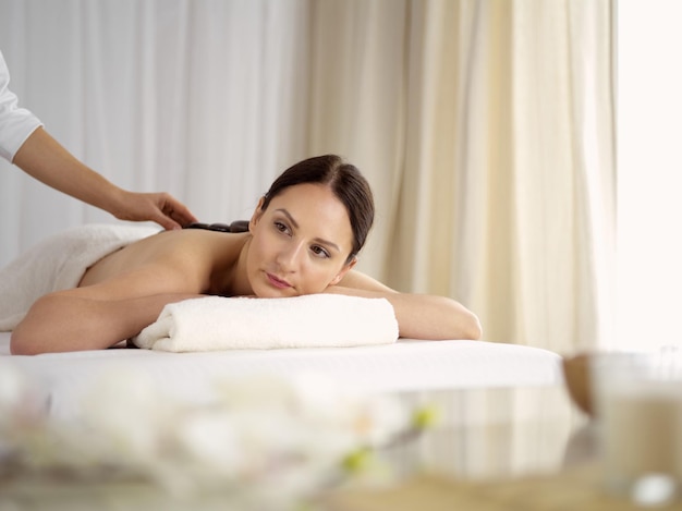 Ładna brunetka kobieta korzystających z leczenia gorącymi kamieniami w salonie spa. Pojęcie piękna.