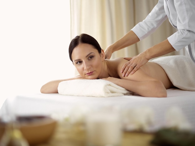 Ładna brunetka kobieta korzystających z procedury masażu pleców w salonie spa. Pojęcie piękna.