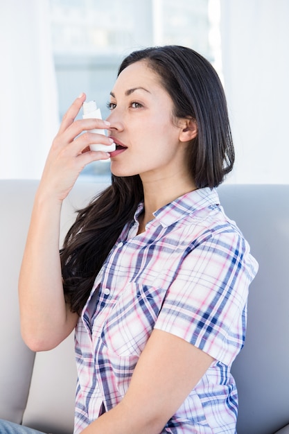 Ładna brunetka używa inhalator na leżance