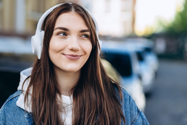 Ładna Brunetka W Białych Słuchawkach Słucha Ulubionej Muzyki Na Zewnątrz