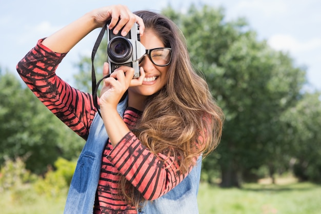 Zdjęcie Ładna brunetka w parku używać retro kamerę