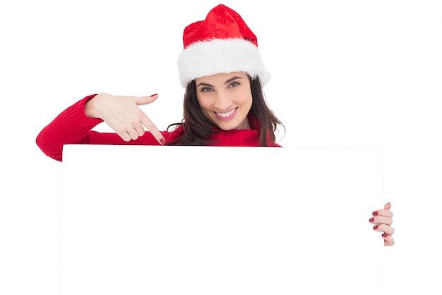 Ładna Brunetka W Santa Kapeluszu Wskazuje Białego Plakat