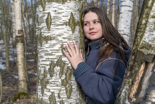 Zdjęcie Ładna dziewczyna na wiosnę na łonie natury przytulona do brzozy.