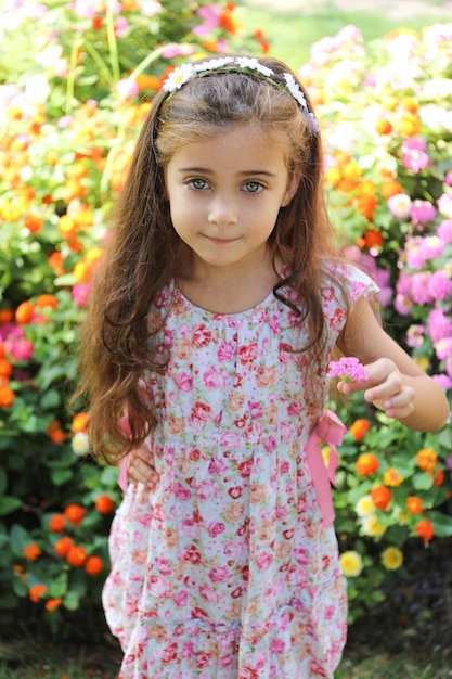 ładna dziewczyna o brązowych włosach i jasnozielonych oczach, szczęśliwa i uśmiechnięta, trzymająca dwa kwiaty