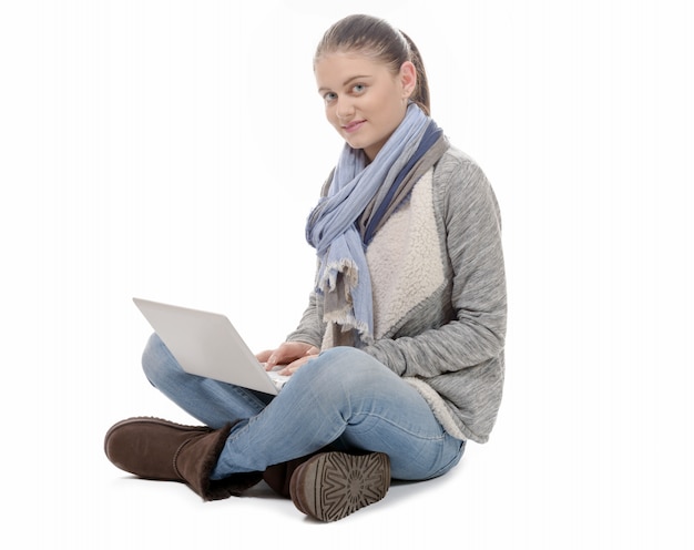 Ładna dziewczyna siedzi ze skrzyżowanymi nogami z laptopem na kolanach