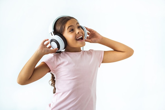Ładna dziewczyna słucha muzyki w słuchawkach na tle białej ściany