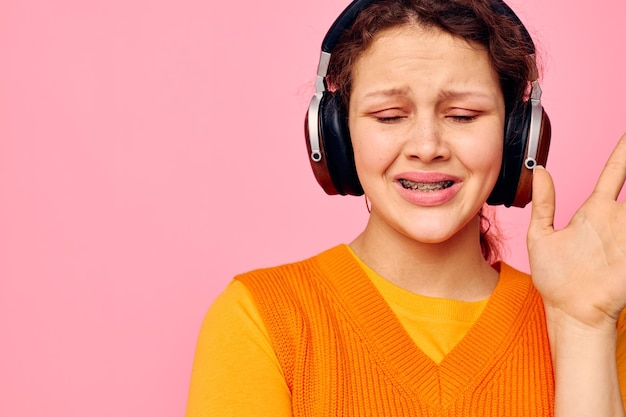 Ładna dziewczyna w pomarańczowym swetrze słuchawki muzyka rozrywka przycięty widok niezmieniony