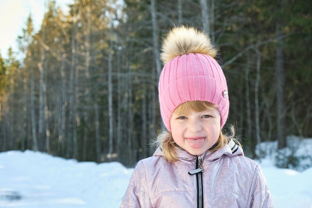 Ładna dziewczyna w słoneczny zimowy dzień na tle śniegu i lasu