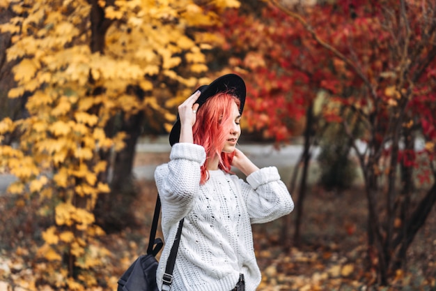 Ładna dziewczyna z czerwonym włosy i kapeluszowym odprowadzeniem w parku, jesień czas.