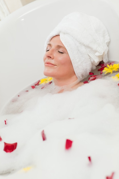 Ładna kobieta bierze relaksującego skąpanie z ręcznikiem na jej głowie