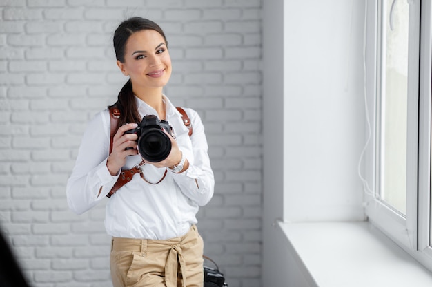 Ładna kobieta jest profesjonalnym fotografem z aparatem dslr