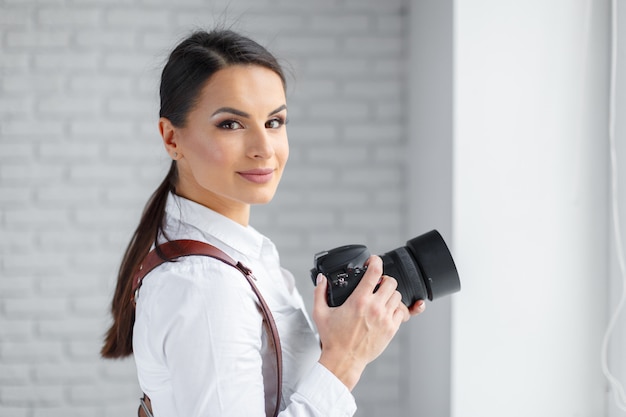 Ładna kobieta jest profesjonalnym fotografem z aparatem dslr