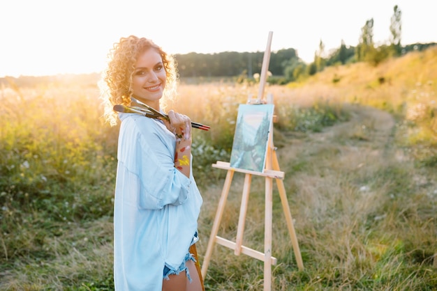 Ładna Kobieta Maluje. Sesja Plenerowa. śliczna Kobieta Rysuje Obrazek O Zachodzie Słońca. Artystka Dziewczyna