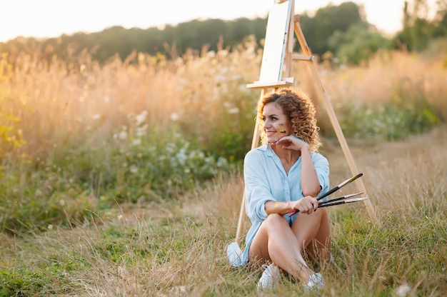 Zdjęcie Ładna kobieta maluje. sesja plenerowa. śliczna kobieta rysuje obrazek o zachodzie słońca. artystka dziewczyna
