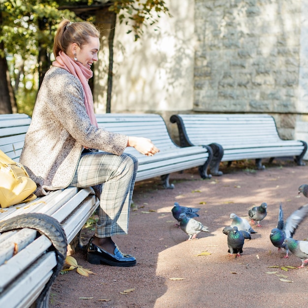 Ładna kobieta odpoczywa w parku i karmi gołębie