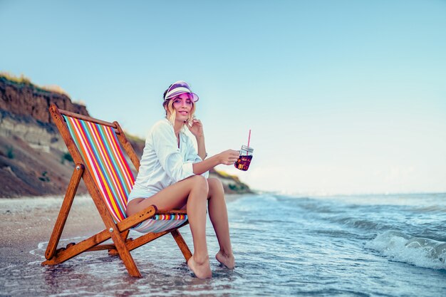 Ładna Kobieta Relaksuje Na Leżak Plaży I Pije Sodowaną Wodę