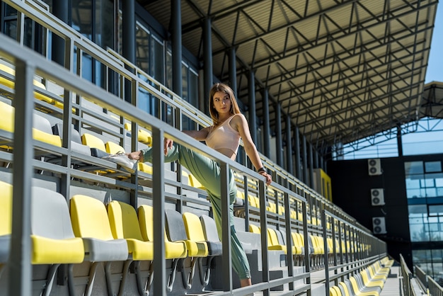 Ładna kobieta robi relaksujące poranne ćwiczenia na trybunie stadionu, przed dniem roboczym