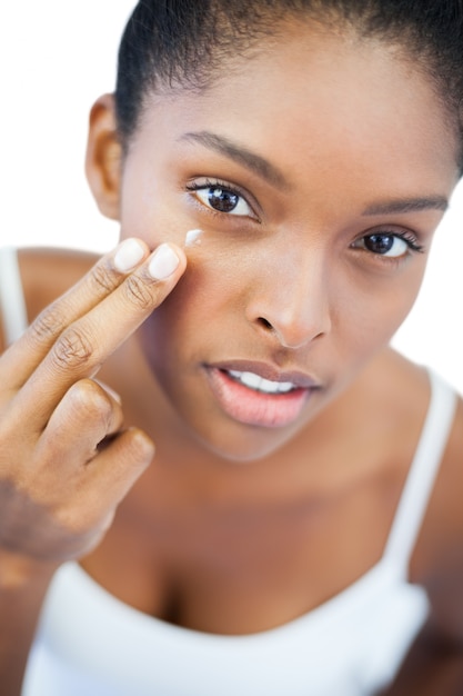 Ładna kobieta stawia moisturizer na jej twarzy