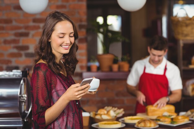 Ładna kobieta trzyma texting i filiżankę kawy