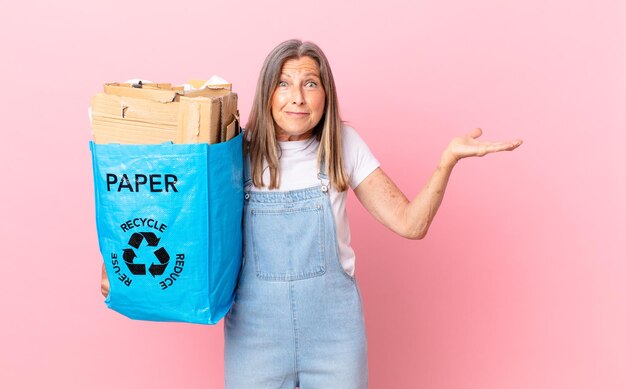 Ładna kobieta w średnim wieku czuje się zdziwiona, zdezorientowana i wątpi w koncepcję recyklingu kartonu