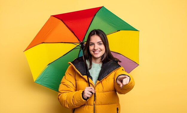 Ładna kobieta, wskazując na aparat wybierając ciebie. koncepcja zima i parasol