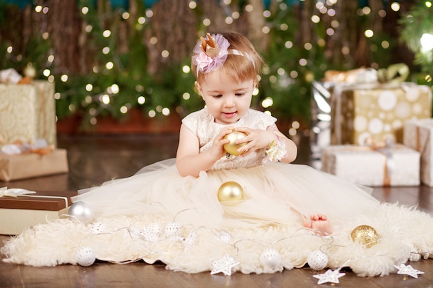 Ładna mała dziewczynka w biel sukni bawić się i jest szczęśliwy o bożonarodzeniowe światła