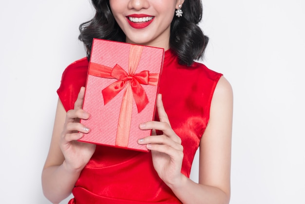 Ładna młoda Azjatka ubrana w czerwoną sukienkę z prezentem
