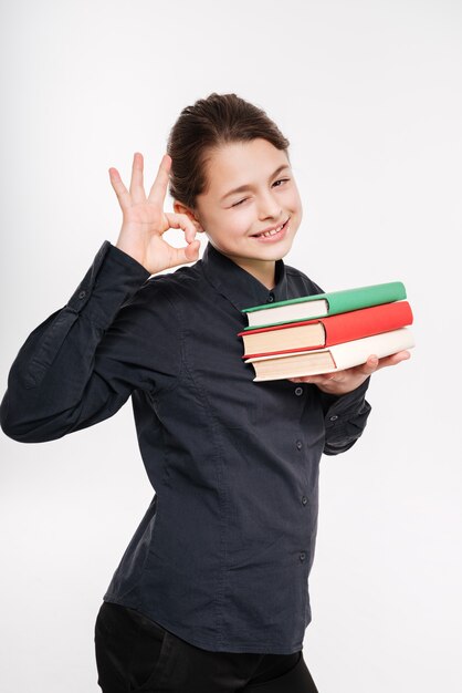 Ładna młoda dziewczyna trzyma książki i robi dobrze gest
