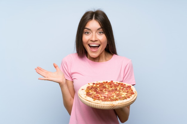 Ładna młoda dziewczyna trzyma pizzę z szokującym wyrazem twarzy
