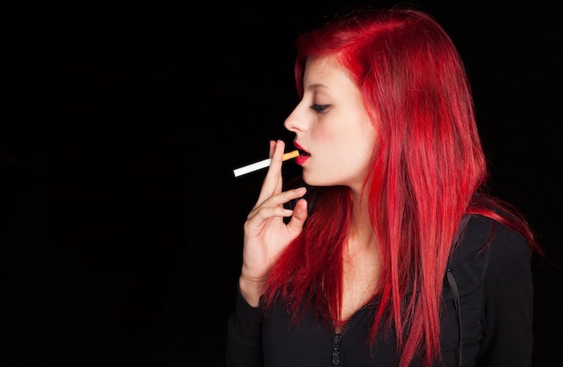 Ładna młoda kobieta dymi papieros przy nocą