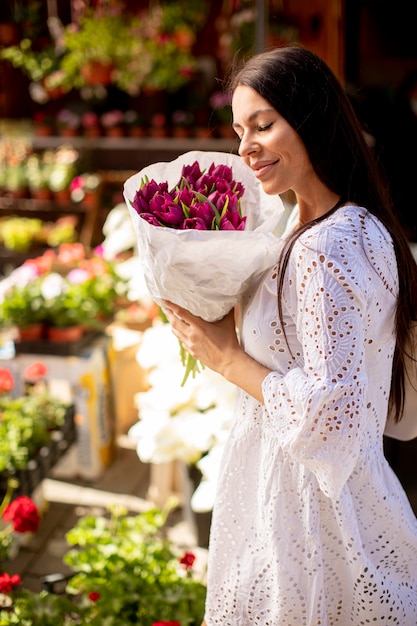 Ładna młoda kobieta kupuje kwiaty na targu kwiatowym