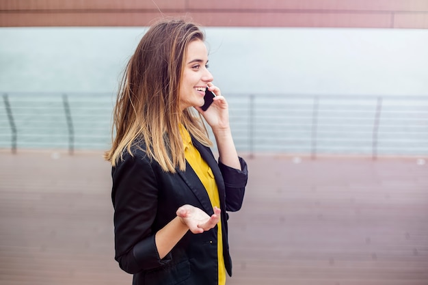 Ładna młoda kobieta opowiada na telefonie komórkowym outdoors