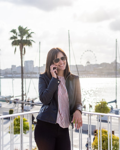 Ładna młoda kobieta opowiada na telefonie komórkowym w Malaga, słoneczny dzień