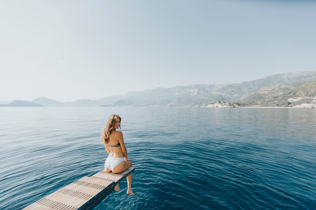 Ładna młoda kobieta relaksuje na jachcie na morzu przy słonecznym dniem