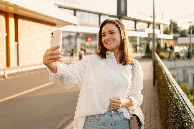 Ładna młoda kobieta robi sobie selfie telefonem podczas spaceru