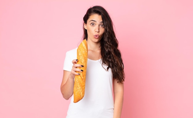 Ładna młoda kobieta trzyma bagietkę z chlebem