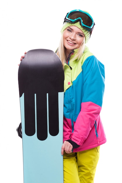 Ładna młoda kobieta w narciarskim stroju chwyta snowboard