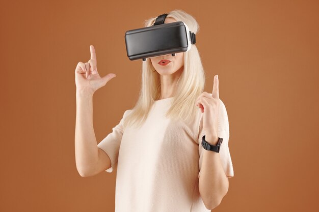 Ładna młoda kobieta w okularach wirtualnej rzeczywistości skierowanymi w górę palcami wskazującymi