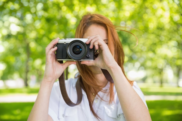 Ładna rudzielec bierze fotografię w parku