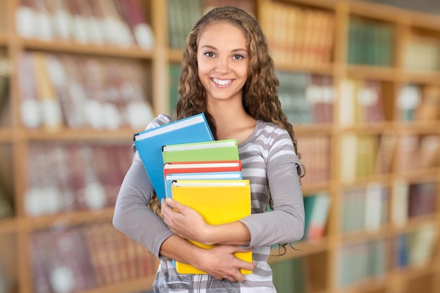 Ładna studentka otoczona książkami z biblioteki