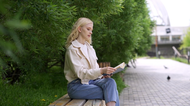 Ładna Studentka Studiująca Literaturę Na Studiach. ładna Młoda Kobieta Szczęśliwie Czyta Książkę W Parku. 4k Uhd