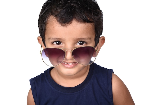 Ładne dziecko w okularach przeciwsłonecznych. Piękno uśmiechnięty chłopiec w okularach przeciwsłonecznych gestykuluje biel odizolowywającego na bielu.