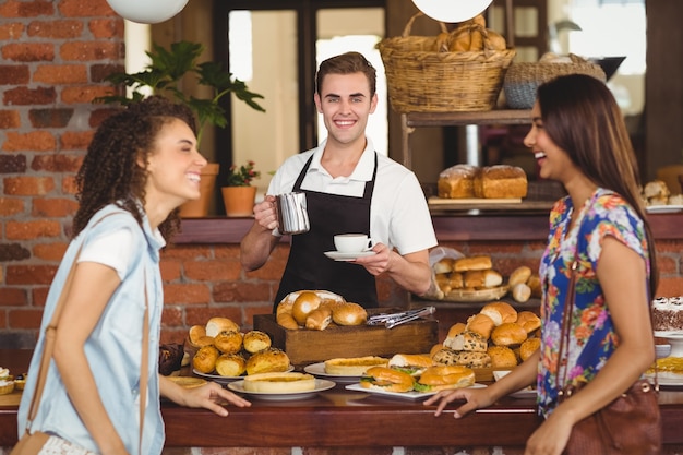 Ładni klienci śmia się przed uśmiechniętym barista