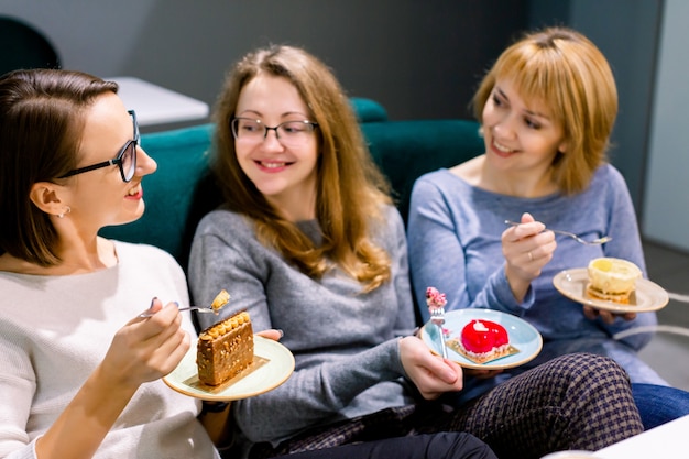 Zdjęcie Ładni żeńscy przyjaciele je smakowitych deserów ciastka w salowej kawiarni, ono uśmiecha się szczęśliwy. spotkanie najlepszych przyjaciół